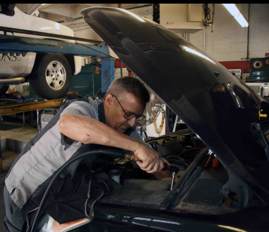 Photo of Kevin Hanks, a transmission specialist, working under the hood of a car
